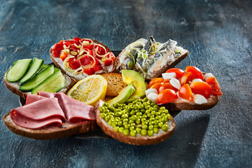 Sticker - Assorted open-faced sandwiches, sandwiches with slices of sourdough with various fillings on a plate - cucumbers, peas, cherry tomatoes, mozzarella, sardines, bell peppers, pastramas, lemon