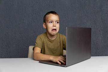 Upset boy sitting and studying on the computer online at quarantine time