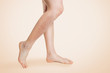 Smooth female legs, with varicose veins and swelling on the lower leg. Beige background. Copy space.The concept of varicose disease