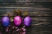 Three Purple Easter Eggs On Dark Wooden Background