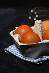 box with fresh eggs and a whisk, vertical