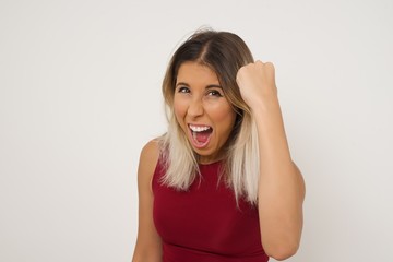 Sticker - Fierce confident European dark-haired woman holding fist in front of her as if is ready for fight or challenge, screaming and having aggressive expression on face. Isolated over gray background.