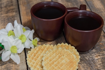 Two cups with coffee on the table. Breakfast for two. A bouquet of daffodils and coffee in bed.