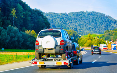 Wall Mural - Car carrying trailer with new vehicle on road in Slovenia reflex