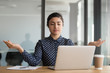 © fizkes - Calm office worker hindu woman sit at desk near laptop folded fingers mudra gesture take break resting at workplace do yoga exercise practise breath technique reduce stress, no anxiety at work concept