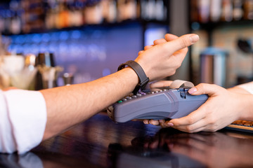 Young client with smartwatch keeping his wrist over payment machine