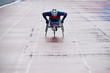 Determined wheelchair racer in sportswear and helmet reaching finish line