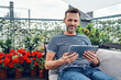 Adult man using digital tablet at apartment balcony