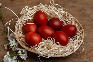 red easter eggs in wicker basket on wooden background