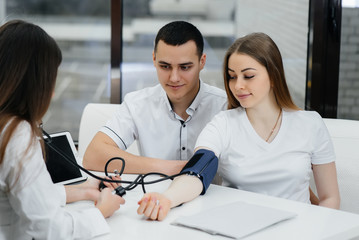 The doctor measures the pressure of a pregnant girl in the clinic. Pregnancy, and health care