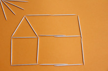 Toothpicks In The Form Of A House And The Sun On An Orange Background