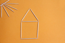Toothpicks In The Form Of A House And The Sun On An Orange Background