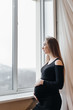 © Andrii - A pregnant girl is breathing fresh air from the window