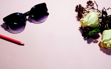 Sunglasses and flowers on a pink background