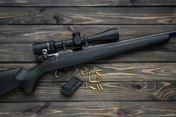 Wall Mural - Bolt small caliber rifle 22lr with an optical sight on a wooden back. Hunting small-caliber weapon on a wooden table.