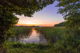 Fototapeta Pomosty - Beautiful and romantic sunset over an old bridge located on a lake in Mazury, also called as the region of lakes of Poland.