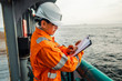 © Igor Kardasov - Filipino deck Officer on deck of offshore vessel or ship , wearing PPE personal protective equipment. He fills checklist. Paperwork at sea