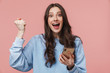 © Drobot Dean - Image of excited young woman making winner gesture and using cellphone