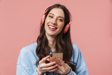 Wall Mural - Image of delighted woman laughing while using headphones and cellphone