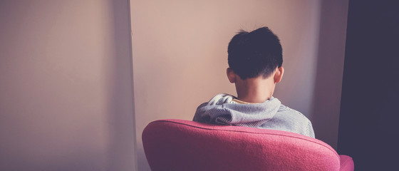 Wall Mural - Sad preteen boy sitting alone in chair facing wall, depressed,introvert,  autism awareness, children mental health,psychology teen autism spectrum disorder, social distancing, self isolation concept