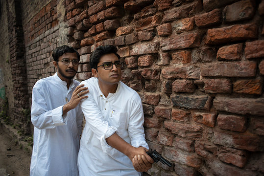 An young Indian Bengali detective and his assistant with traditional wear going to attack with a gun in a winter morning in a crime scene.