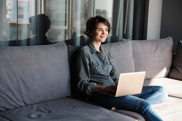 Sticker - Image of nice young pleased woman using laptop and smiling