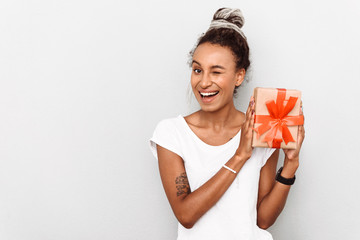 Positive optimistic happy young african woman with dreads isolated over white wall background holding present gift box.