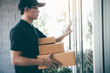 © wutzkoh - Young asian courier is using the hand of the knock at the door to deliver the goods.