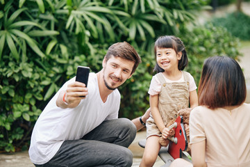 Wall Mural - Happy young father taking selfie with little daughter when spending weekend in park together