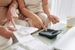 © DragonImages - Close-up image of senior woman and her adult daughter calculating sum of unpaid bills