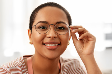 people, vision and leisure concept - portrait of happy smiling african american woman in glasses at home