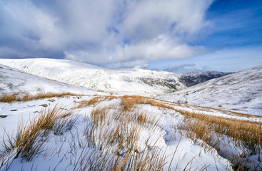 Sticker - A snow covered Glenridding Beck below Catstye Cam with Glenridding Screes in the distance on a sunny winters day in the Lake District, UK.