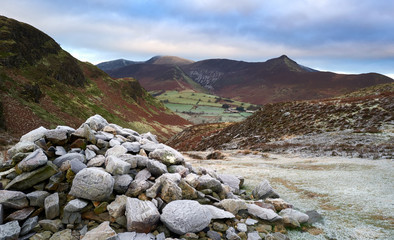 Wall Mural - Pile of stones marking the way in a frost covered valley below the summit of Cat Bells, Derwent Fells with the mountain summit of Causey Pike in the distance. Lake District UK.