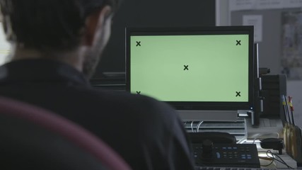 Professional engineer looks monitor with Green Mock-up Screen and integrated development programming on display. Monitor with Green Screen. Great for mock-up usage.