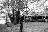 Fototapeta  - black and white photo, a young guy in an official suit plays a game, throws a circle on the lawn
