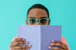 © Carlos David - Portrait of a reader with glasses holding book and looking at camera, isolated on blue