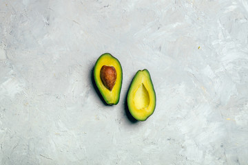 Avocado cut in halves with seed on white grunge background.