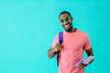 © Carlos David - Portrait of a happy young man in pink shirt with glasses, books and school backpack looking at camera, isolated on blue