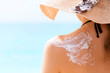 © sosiukin - Young girl in straw hat is applying sunscreen on her back to protect her skin