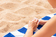 © sosiukin - Closeup of woman putting sun cream on hand before sunbathing at the beach