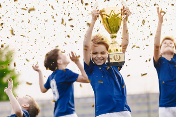 Wall Mural - Sport team celebrating success. Happy boys rising golden trophy on celebration. Children winning sports soccer tournament competition. Inter-school soort competition