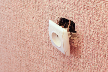 An old broken electrical outlet fell out of the wall, danger of electric shock