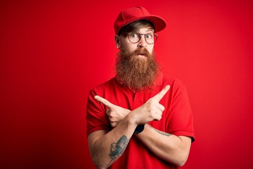 Wall Mural - Young handsome delivery man wearing glasses and red cap over isolated background Pointing to both sides with fingers, different direction disagree