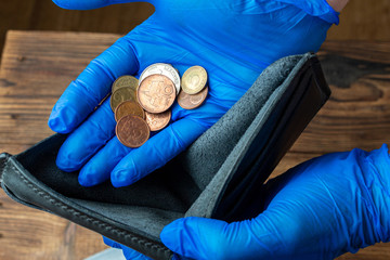 empty blue wallet in hands in medical gloves holding coins after financial economic crisis