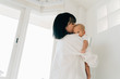 © twinsterphoto - Asian family of mother holding a newborn baby boy over mom shoulder at home. Parenting kid with love