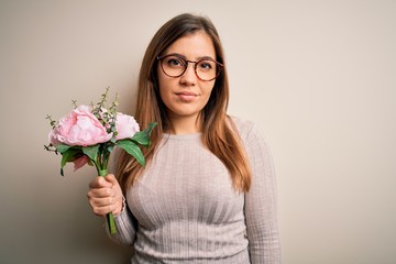 Sticker - Young blonde woman holding beautiful romantic floral bouquet over isolated background with a confident expression on smart face thinking serious