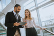 © BGStock72 - Senior business man and his young female colleague standing in office with digital tablet
