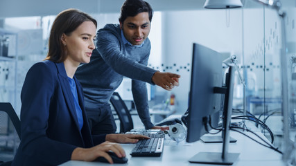 Poster - Modern Factory Office: Male Project Supervisor Talks to a Female Industrial Engineer who Works on Computer. Professional Teamwork, Young Specialists Solving Problems and Driving Technological Progress