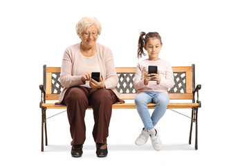 Poster - Child and an elderly woman sitting on a bench and typing on mobile phones