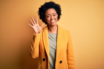 Sticker - Young beautiful African American afro businesswoman with curly hair wearing yellow jacket showing and pointing up with fingers number five while smiling confident and happy.